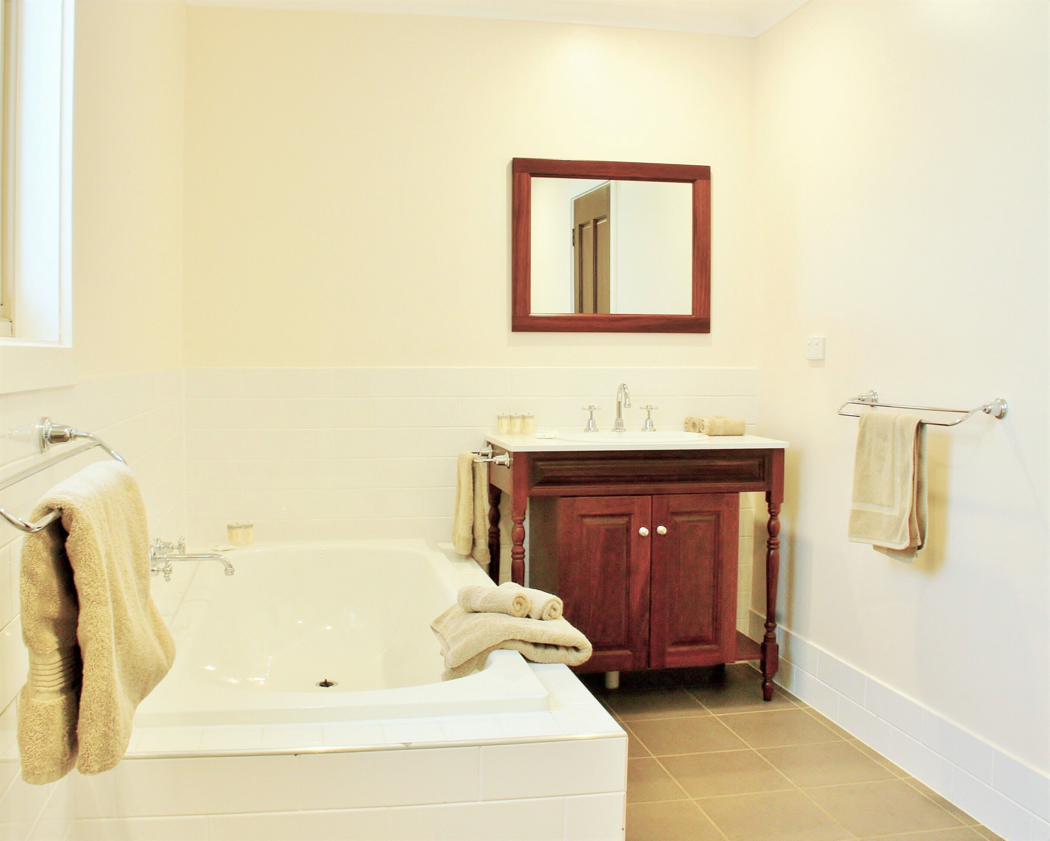 A bathroom with a bathtub, a sink, a vanity with a mirror, and towels on the wall.