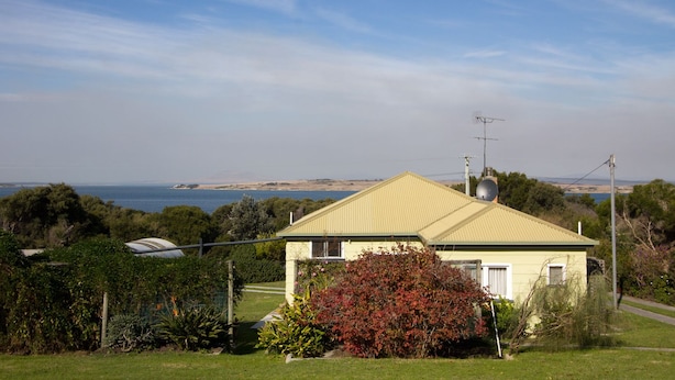Een huis met een groen dak, omringd door groen en uitzicht op zee.