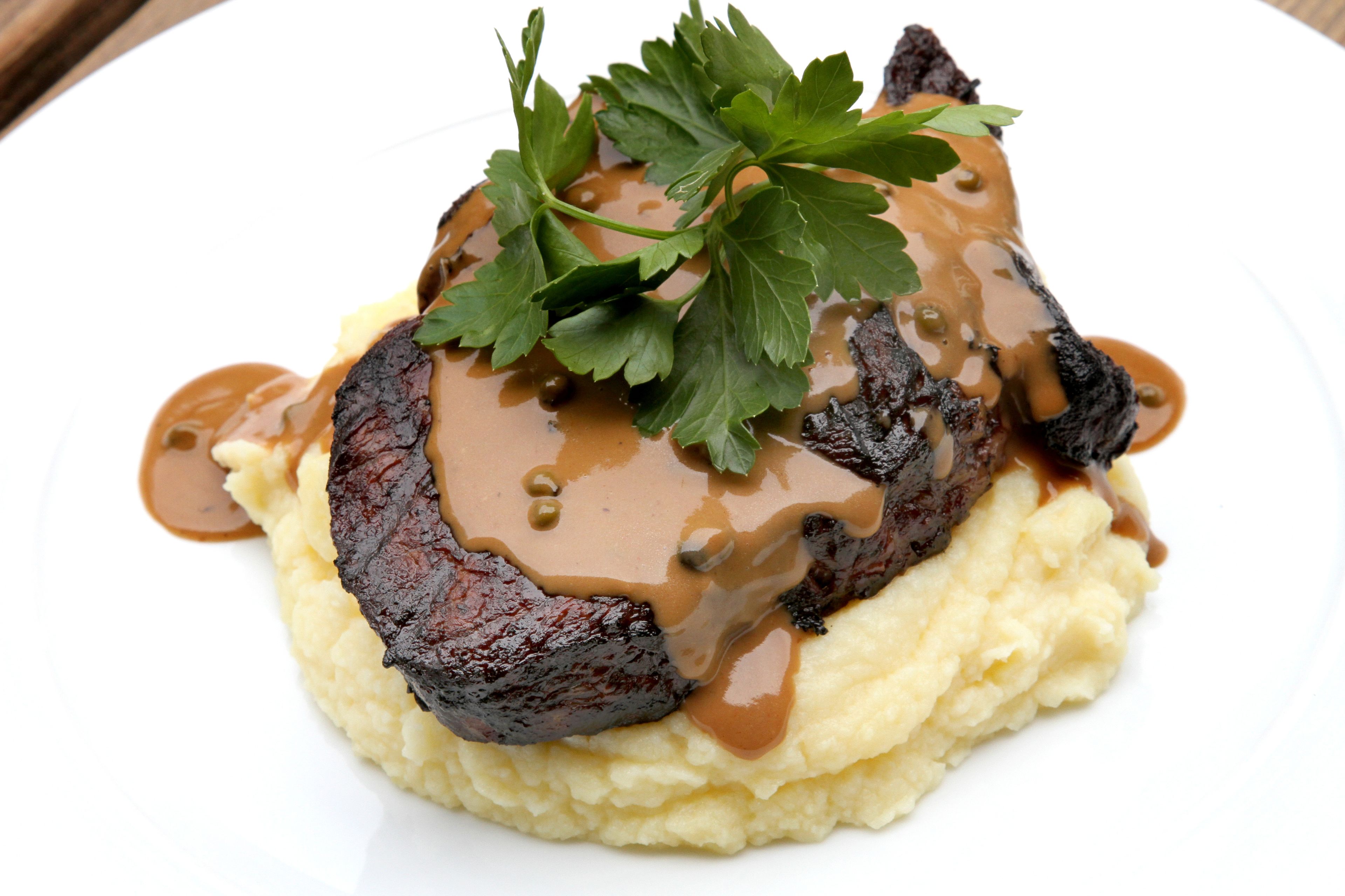 A plate of steak with gravy and mashed potatoes.