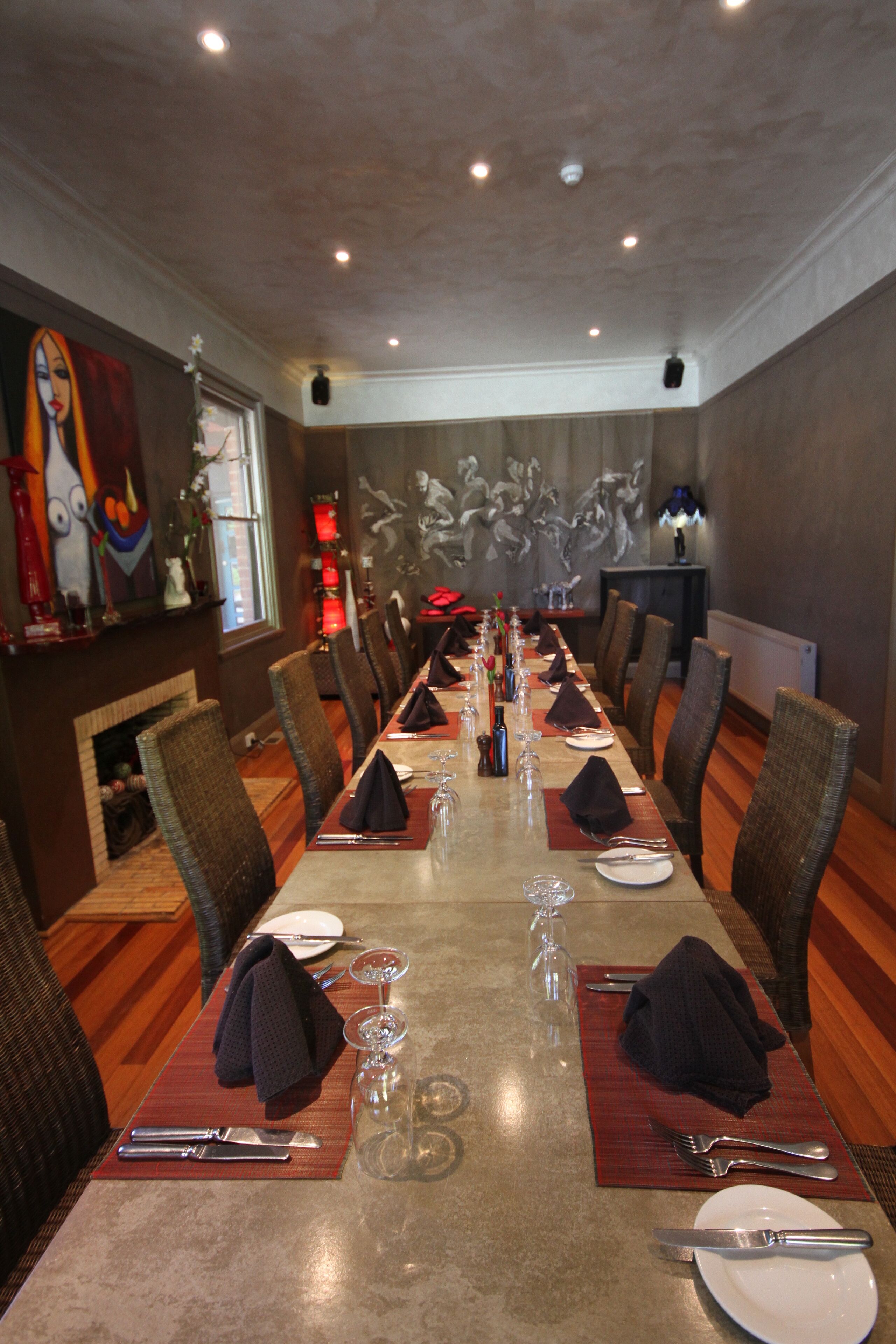 Una larga mesa de comedor preparada para una comida en un restaurante, con sillas a ambos lados.