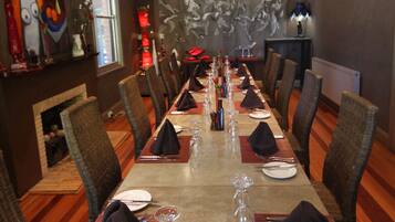 Una larga mesa de comedor preparada para una comida en un restaurante, con sillas a ambos lados.