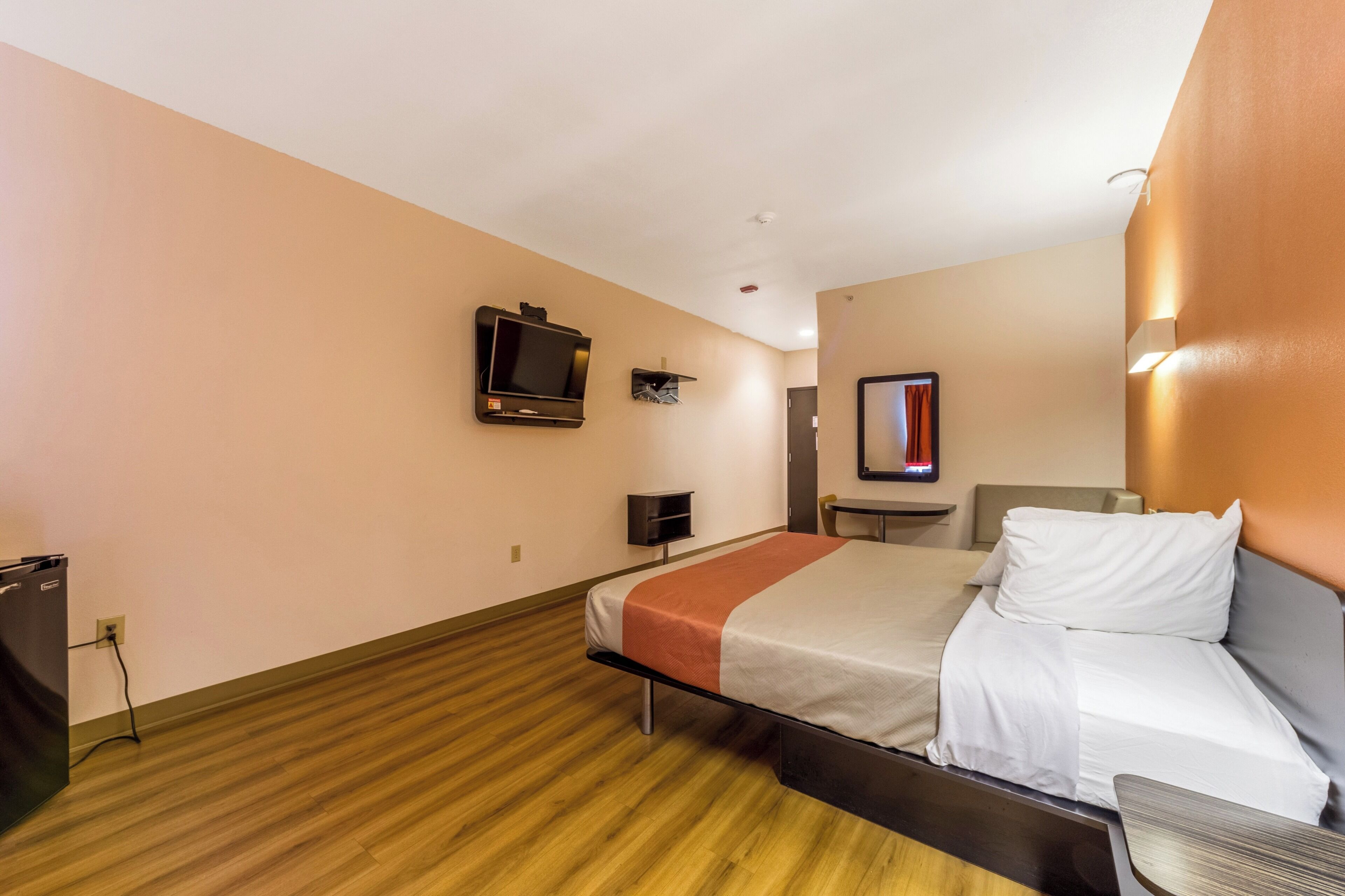 A hotel room with a bed, a television, a desk, and a mirror.