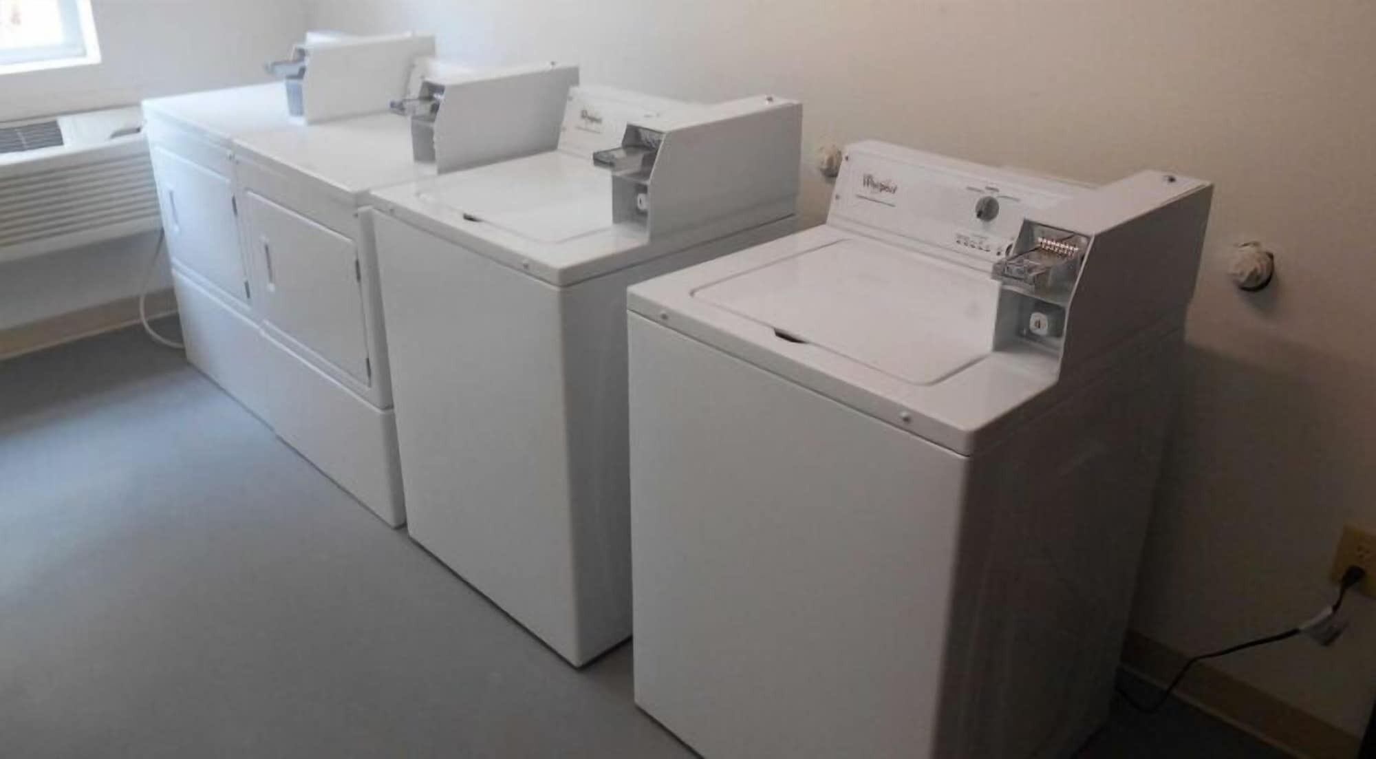A laundry room with two white front-loading washers and dryers.