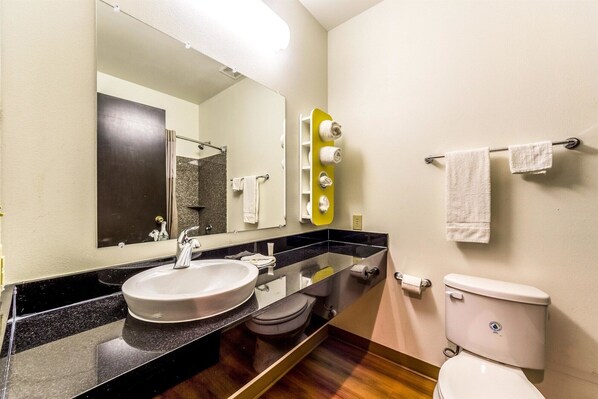 A modern bathroom with a large mirror, a sink, a toilet, and a shower area.