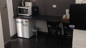 A compact kitchenette with a microwave, coffee maker, and a small trash bin. - Elmore Victoria Hotel Motel (Elmore)