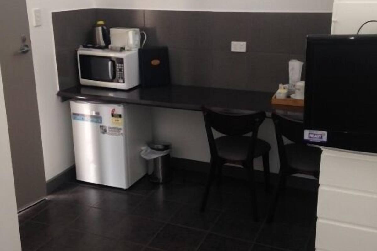 A compact kitchenette with a microwave, coffee maker, and a small trash bin.