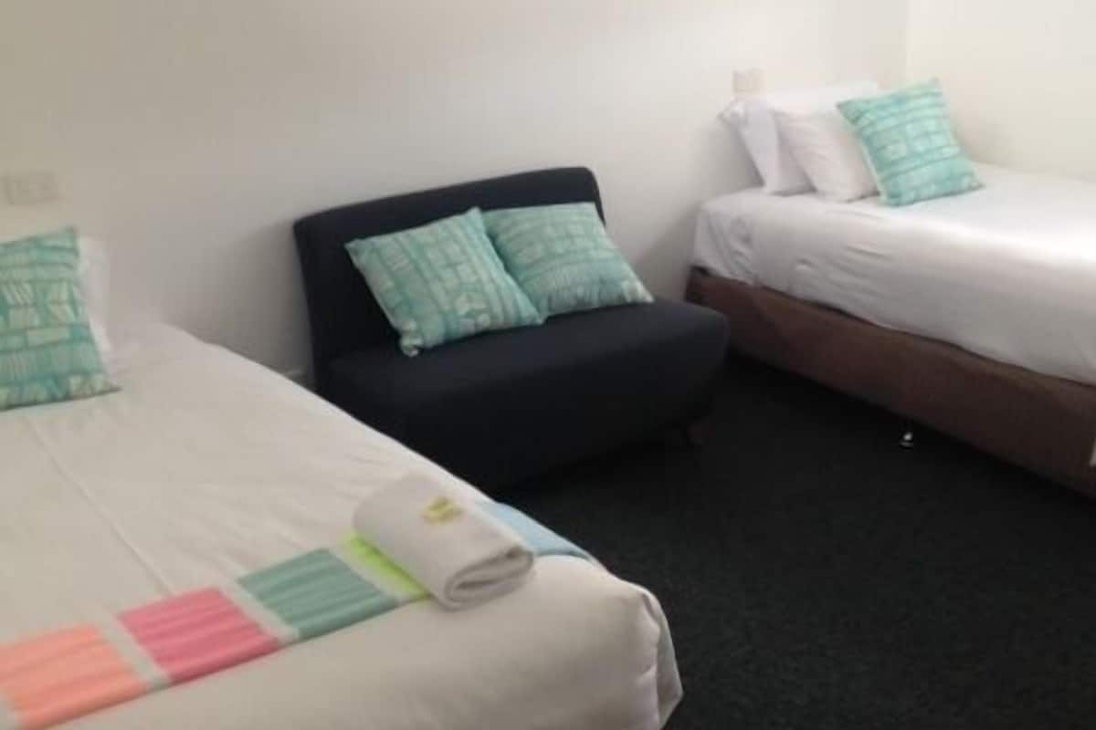 A hotel room with two beds, a black headboard, and a wall-mounted artwork.