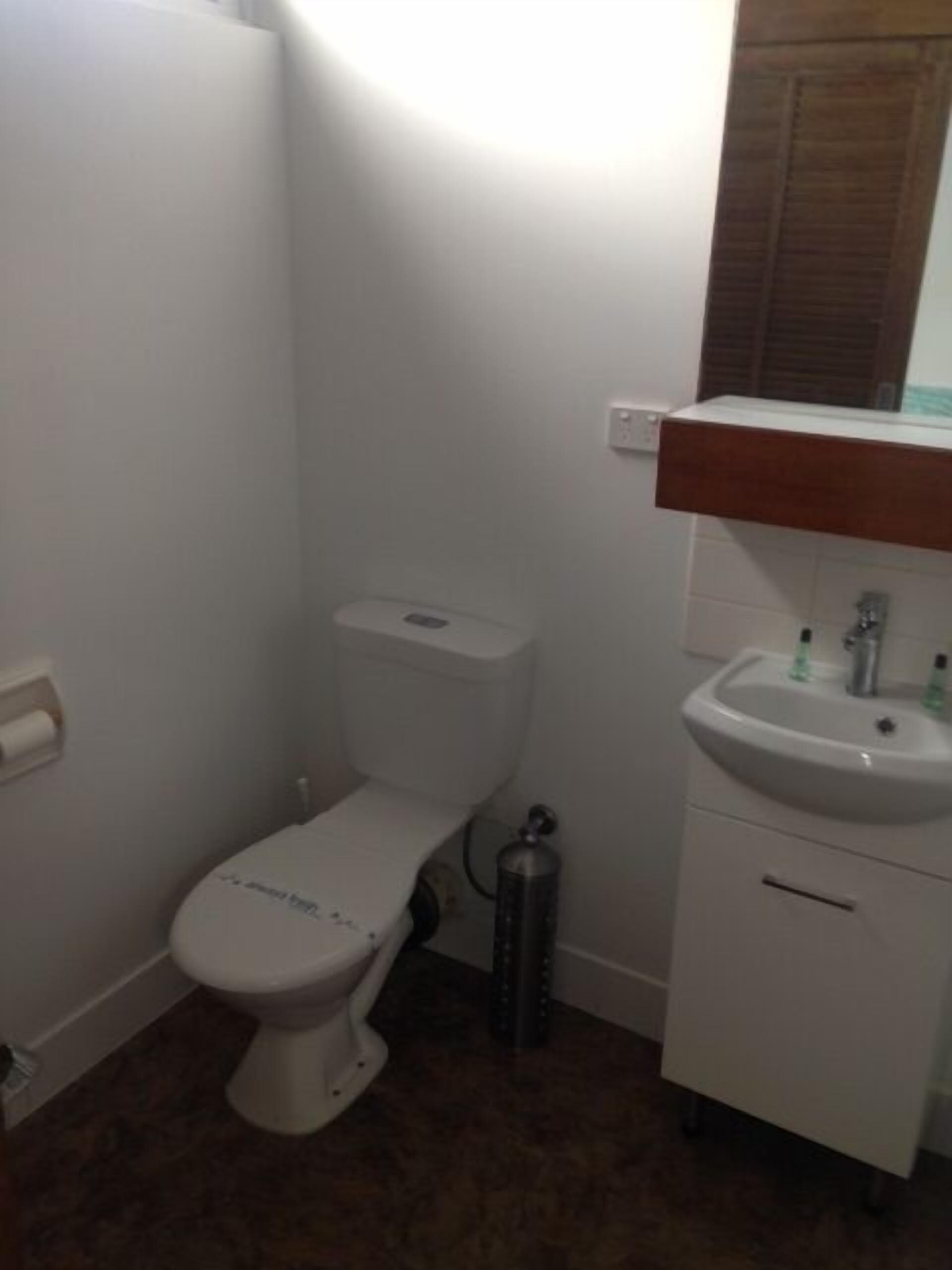A small bathroom with a toilet, sink, and a mirror above the sink.