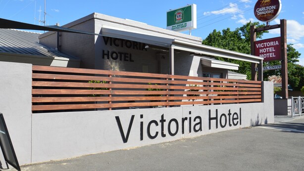 The exterior of Victoria Hotel with a prominent sign, a drive-in bottle shop sign, and a Carlton Draught sign. - Elmore Victoria Hotel Motel (Elmore)