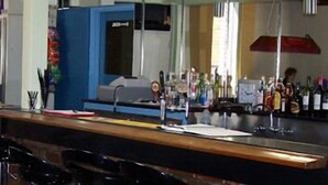 A bar area with stools, a counter, and a display of bottles. - Elmore Victoria Hotel Motel (Elmore)