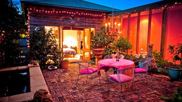 Eine gemütliche Terrasse im Freien mit einem Holzhaus, einem runden Tisch und Stühlen.