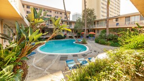 A swimming pool surrounded by lounge chairs and greenery, with buildings in the background. - Cal Mar Hotel Suites (Santa Monica)