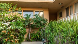 A building with a balcony, a concrete pathway, and various plants. - Cal Mar Hotel Suites (Santa Monica)