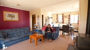 A living room with a blue sofa, a wooden coffee table, and a kitchen in the background. - Black Jack Get-A-Way (Orroroo)