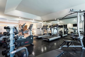 Una palestra con tapis roulant, macchinari per pesi e manubri.