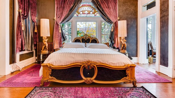 Ein luxuriöses Schlafzimmer mit einem großen Bett, aufwendigen Vorhängen und einer Kristallleuchter.