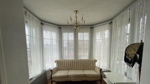Ein Zimmer mit einem beigefarbenen Sofa, einem weißen Tisch und einer Chandelüster.