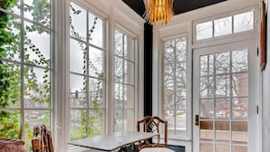 Ein Zimmer mit großen Fenstern, Holzboden und zwei Korbstühlen.
