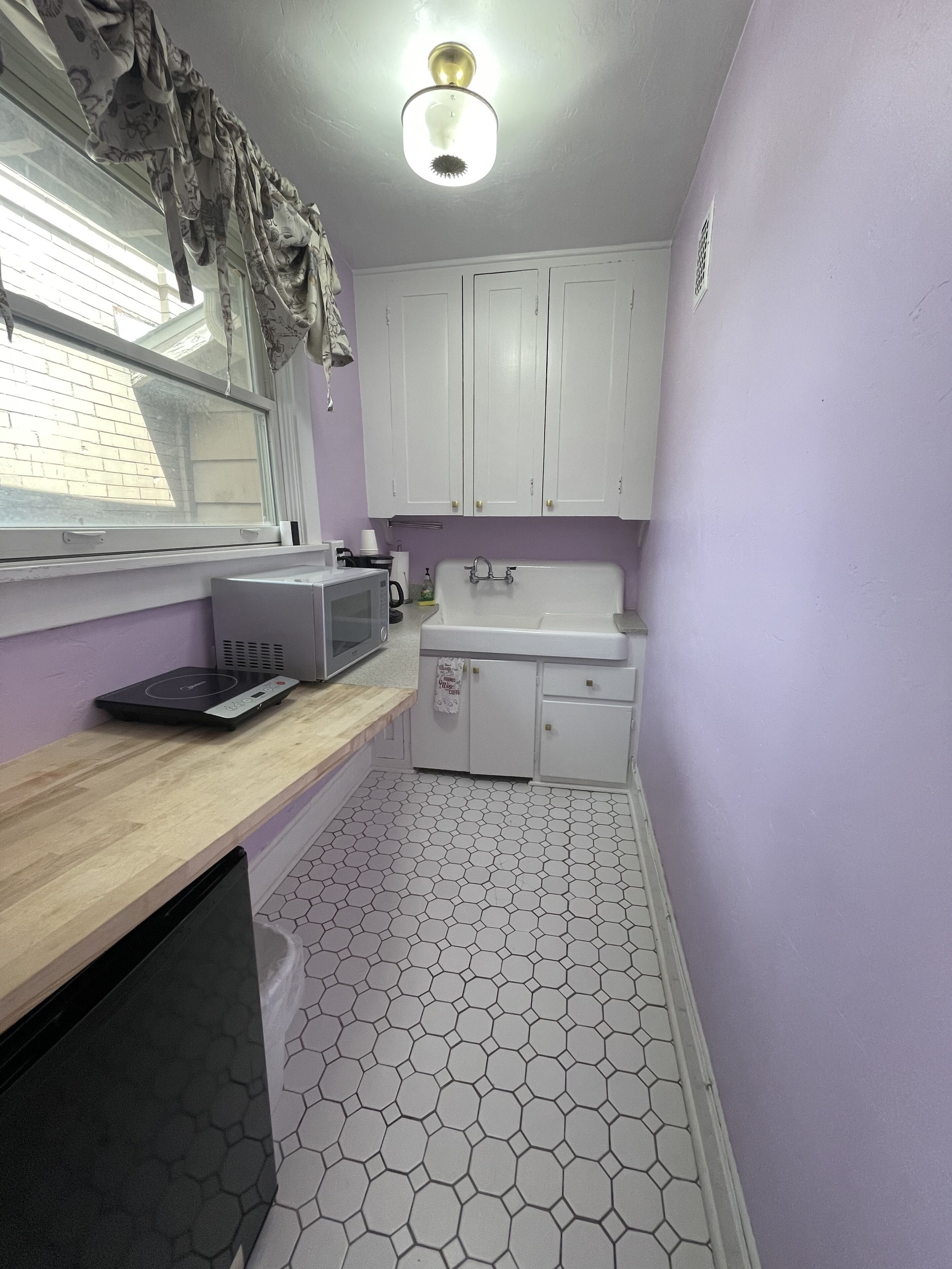 A compact kitchen with white cabinets, a microwave, a toaster, and a sink.