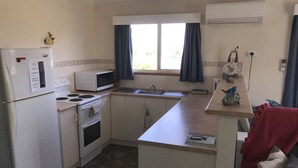 Una cocina compacta equipada con refrigerador, microondas, estufa, horno y pileta.