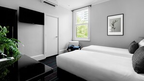Una habitación de hotel moderna con una cama, un televisor, una ventana con vistas y un cuadro en la pared.