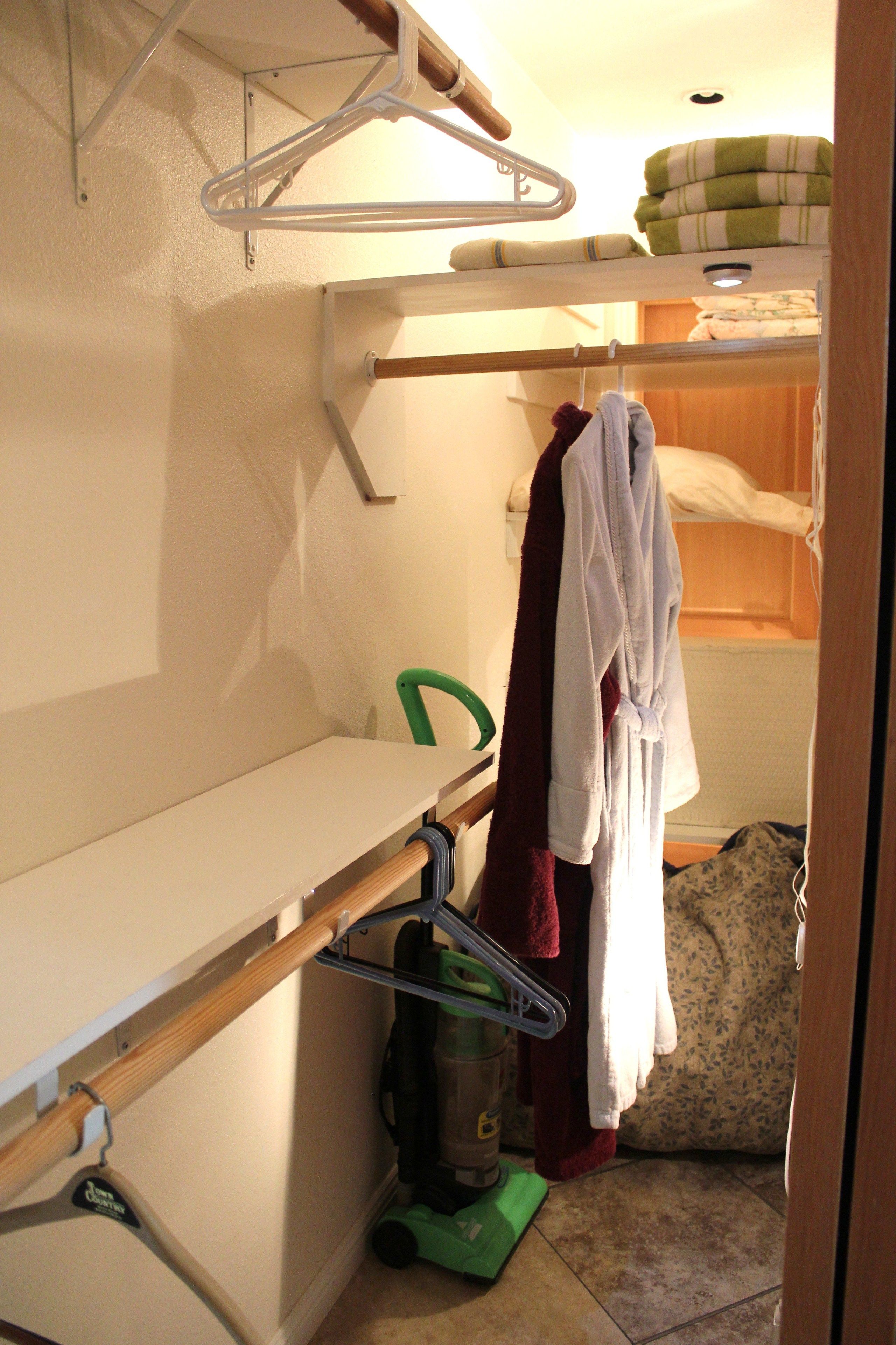 A compact room with bunk beds, a small table, a vacuum cleaner, and a green chair.