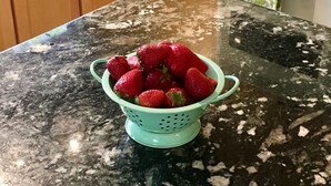 Eine Küchenarbeitsplatte mit einer Siebkorb voller Erdbeeren.