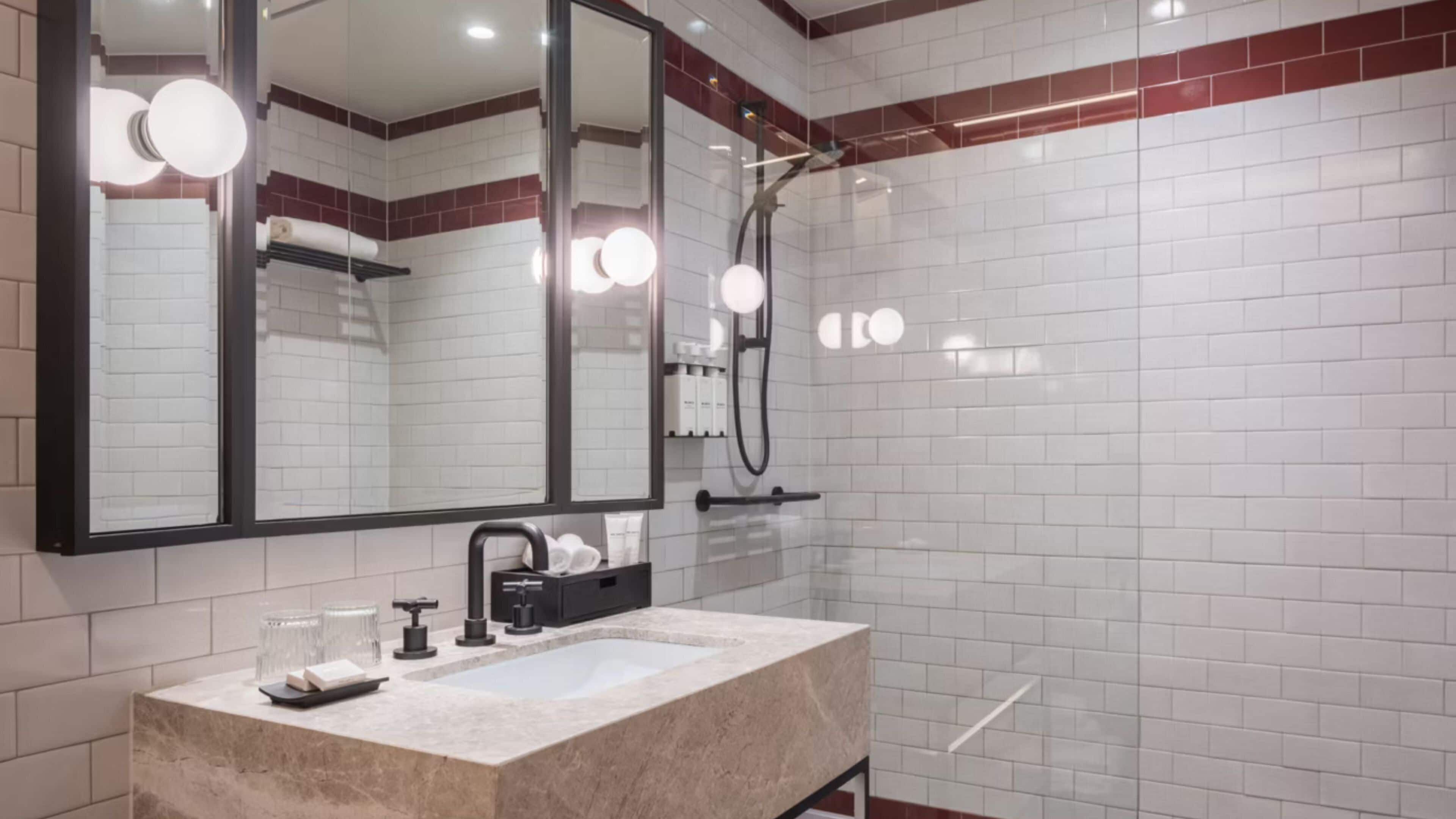 A modern bathroom with a large mirror, a sink, and a shower.