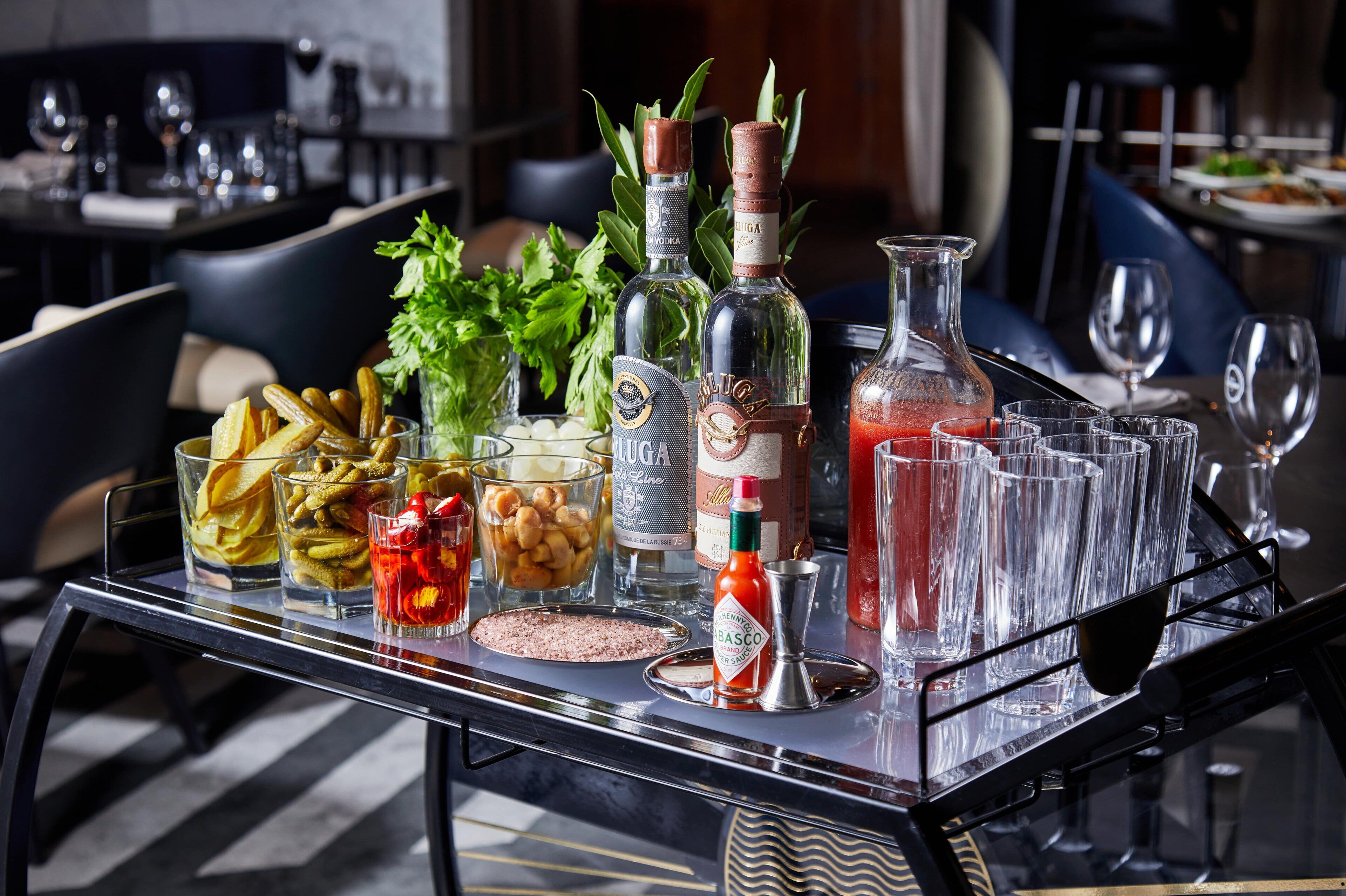 A bar area with various bottles, glasses, and a tray of food.