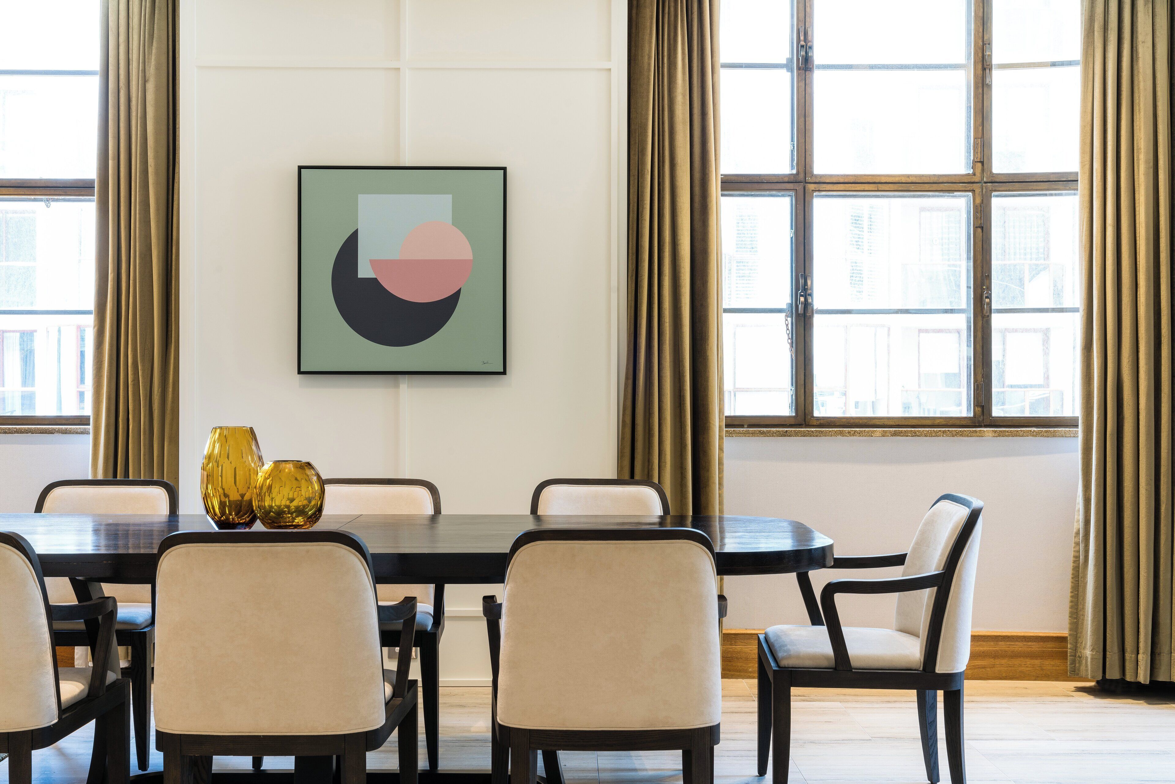 A dining area with a table, chairs, and a framed artwork on the wall.
