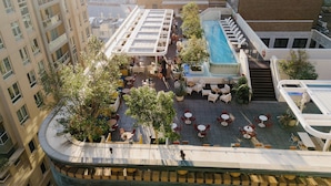 Un área de piscina en la azotea con mobiliario exterior y un pequeño jardín.