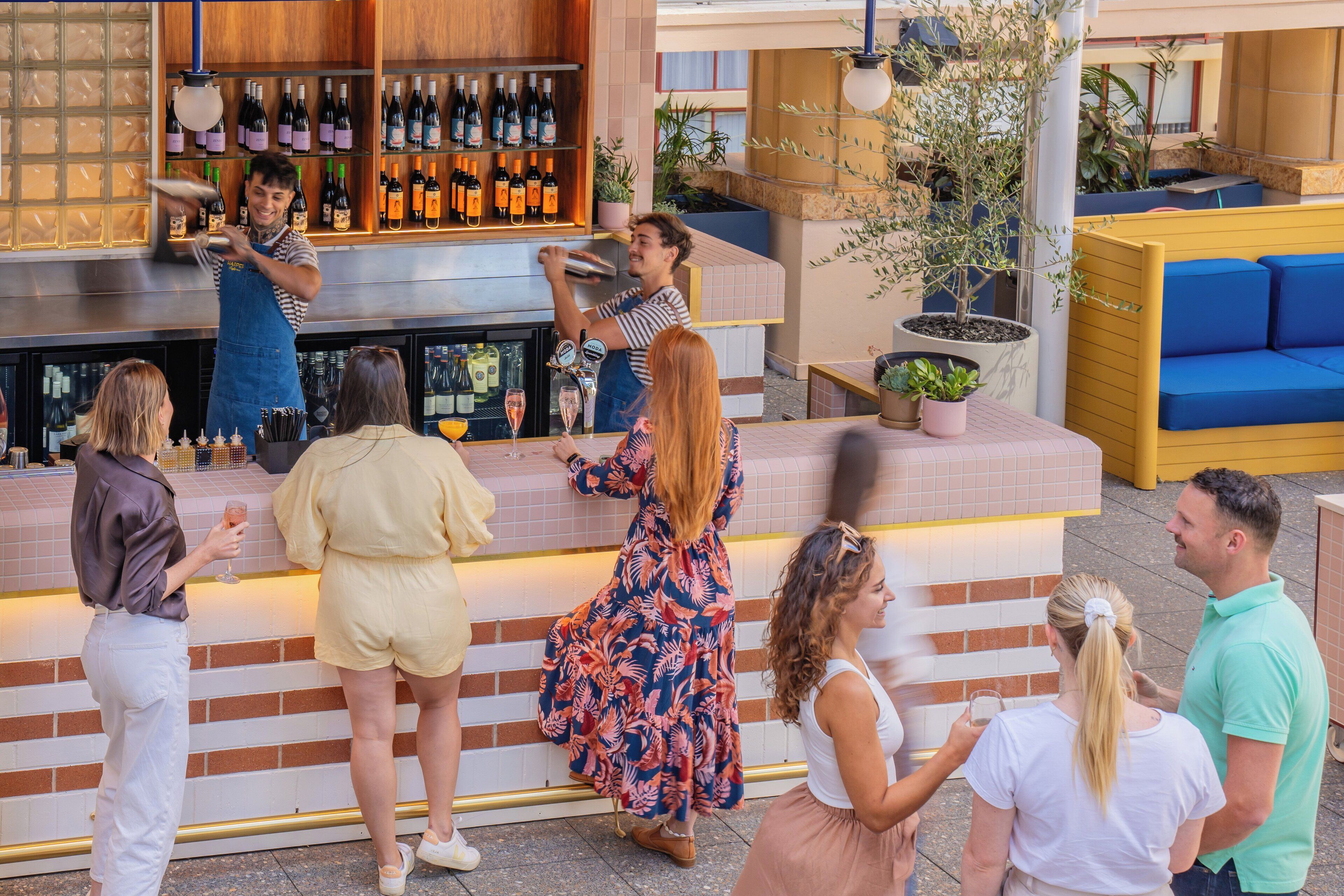 A bar area with a bartender, a wine rack, and seated guests.