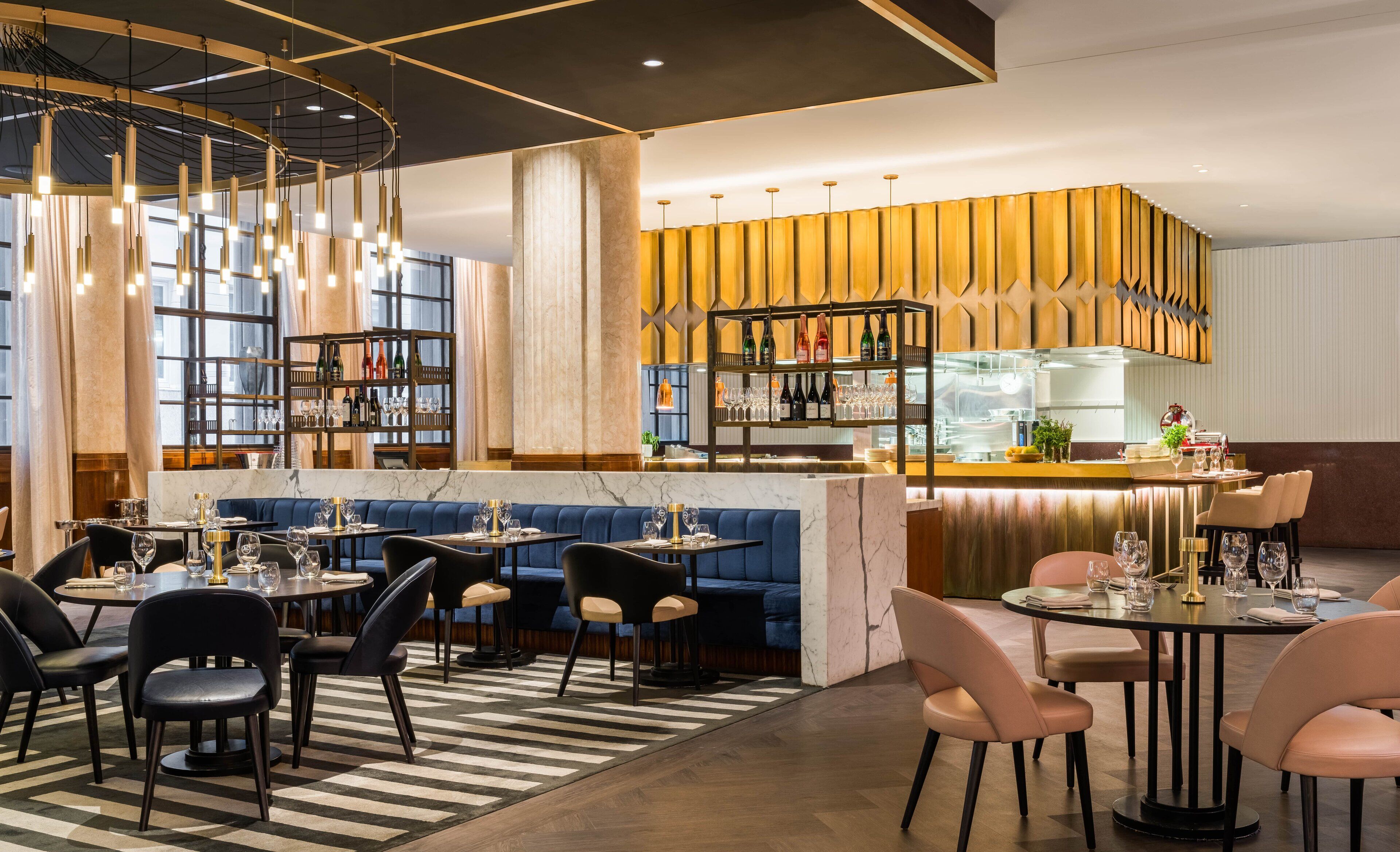 A modern restaurant with a bar area, seating arrangements, and a decorative ceiling.