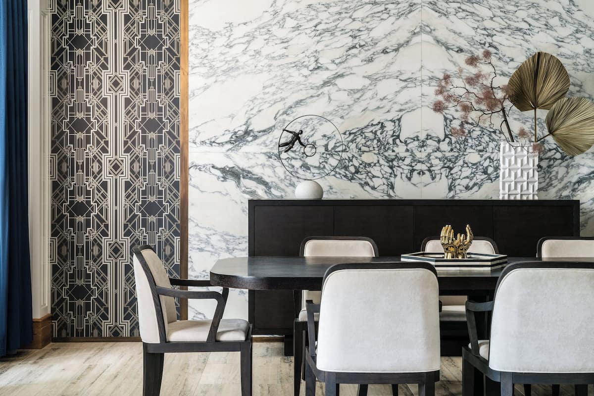 A modern dining area with a marble wall, geometric patterned wallpaper, and a minimalist table setting.
