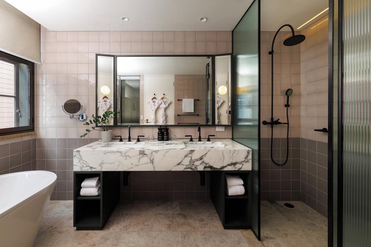 A modern bathroom with a marble sink, two towel racks, a large mirror, and a glass-enclosed shower.