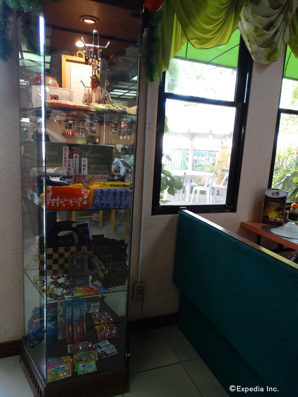A glass display case with various items, a window with a view of the outside, and a teal-colored bench. - Idea Pension House (Jagna)