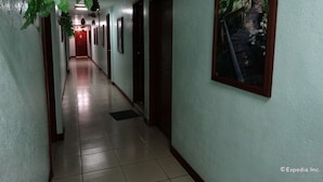 Un pasillo con suelo de baldosas, puertas y un cuadro en la pared.