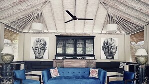 A spacious room with a high ceiling, a ceiling fan, a large sofa, two armchairs, a coffee table, and a cabinet with glass doors. - Elysium (Unawatuna)