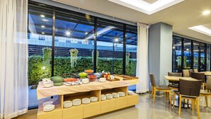 A buffet setup with a variety of dishes and a view of greenery outside. - Livotel Hotel Kaset Nawamin Bangkok (Bangkok)