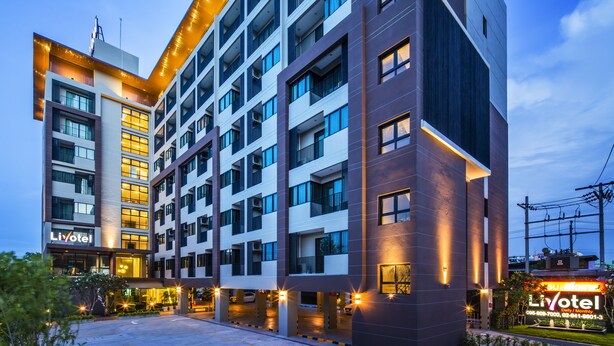 A multi-story hotel with a modern design, featuring a prominent entrance and a parking area. - Livotel Hotel Kaset Nawamin Bangkok (Bangkok)