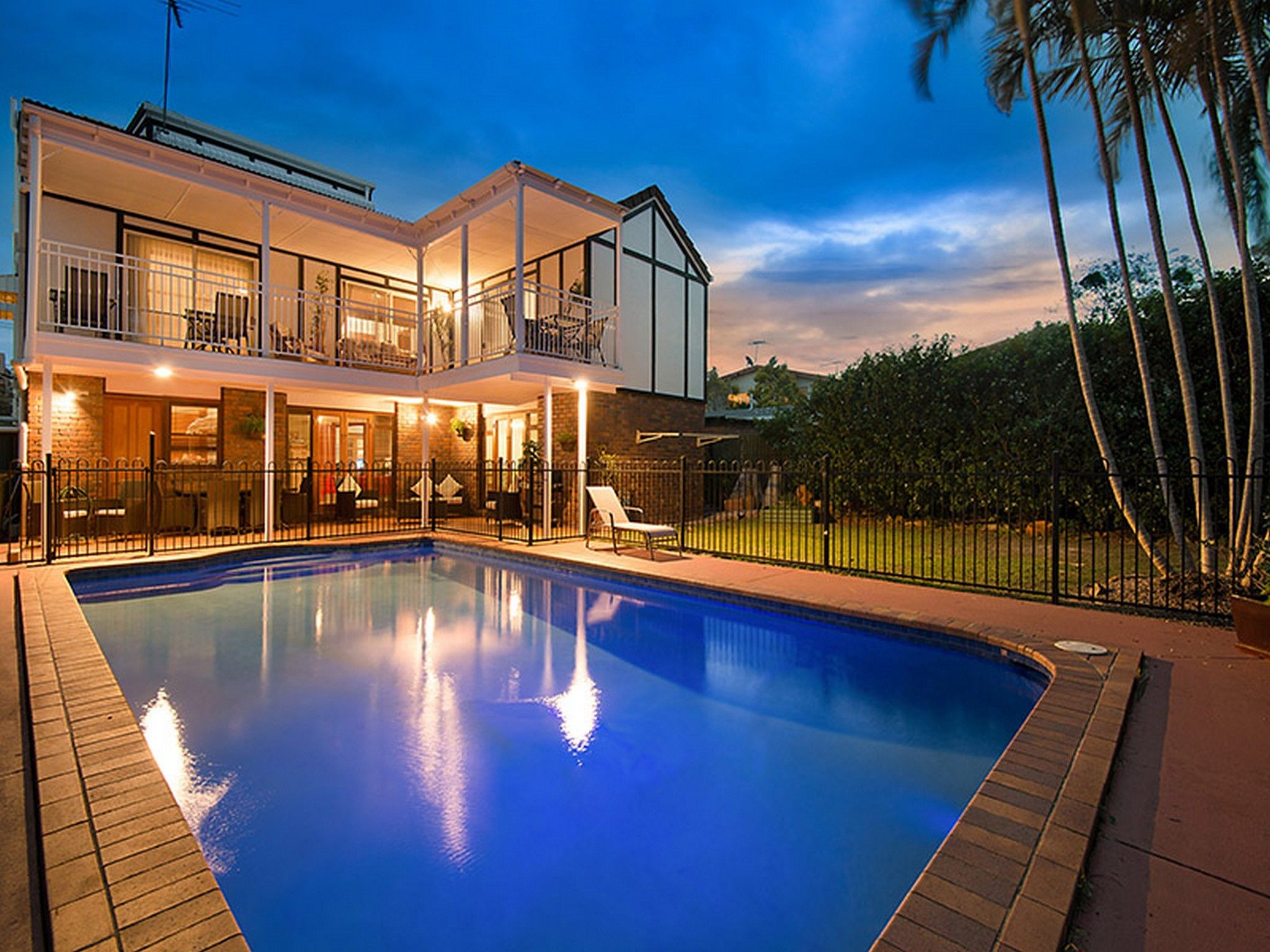 A two-story house with a swimming pool, a balcony, and a fenced yard.