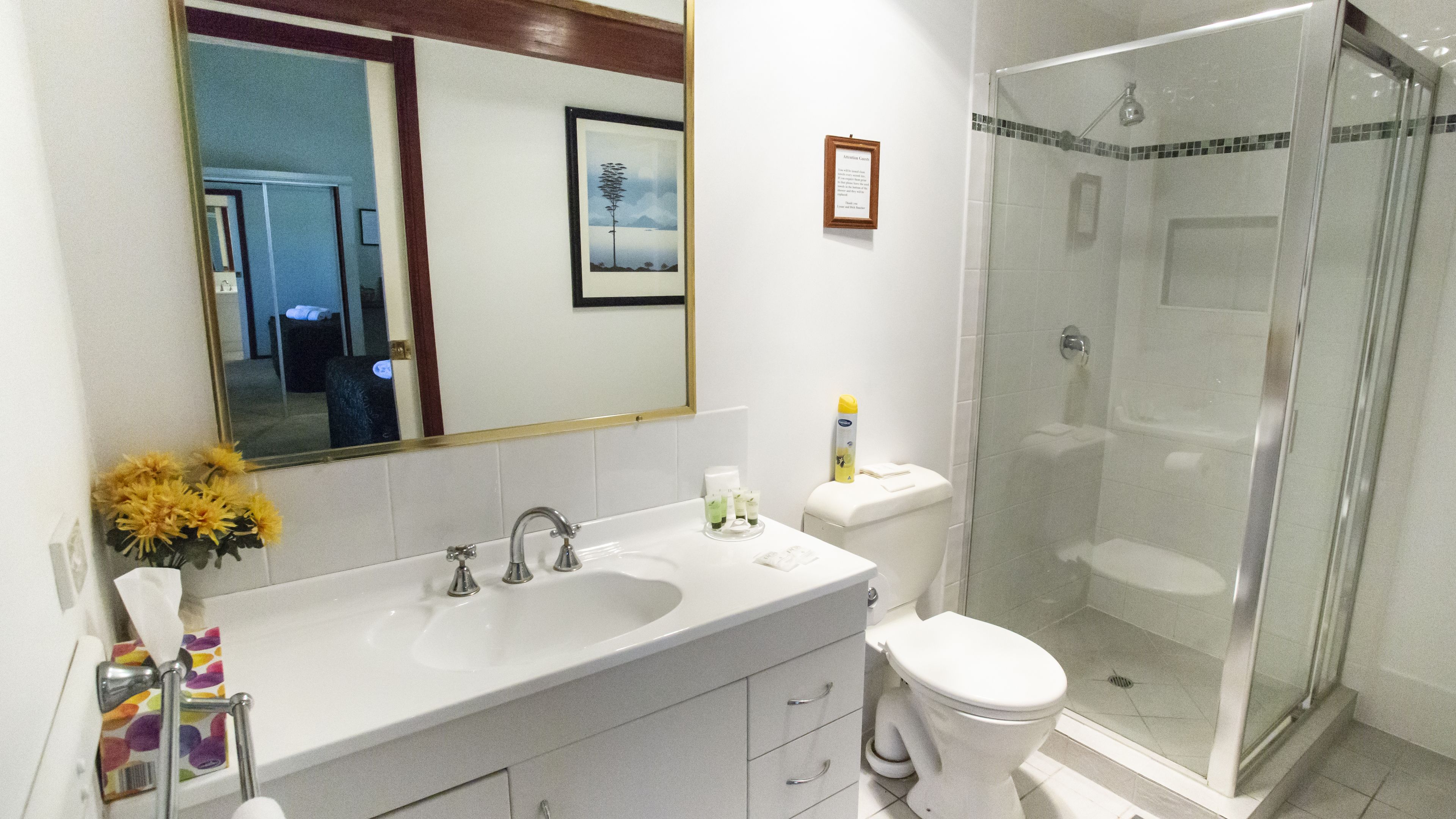 Un bagno con doppio lavabo, water e cabina doccia in vetro.