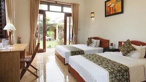 Habitación de hotel con dos camas, un escritorio y una silla. Cuenta con una ventana con cortinas, un cuadro en la pared y vistas al exterior.