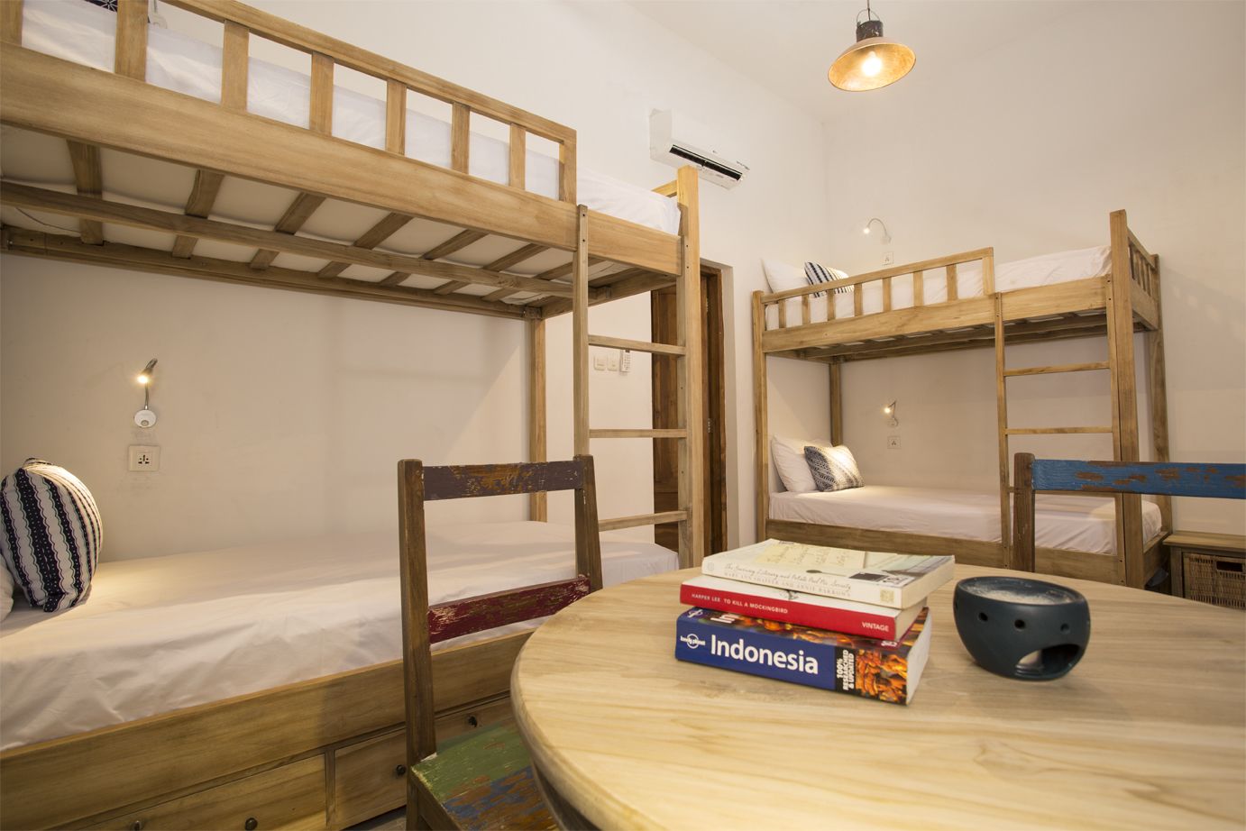Ein Schlafsaalzimmer mit Etagenbetten, einem runden Holztisch und einem Stuhl.