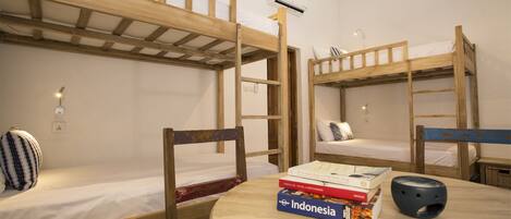 Ein Schlafsaalzimmer mit Etagenbetten, einem runden Holztisch und einem Stuhl.