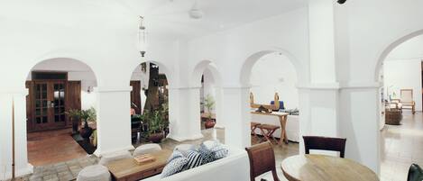 Un interior espacioso con techos altos, arcos blancos y una zona de estar central con una mesa y sillas de madera.