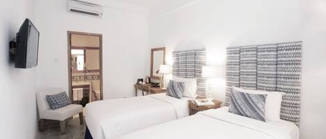 A hotel room with two beds, a TV, a desk, and a mirror.