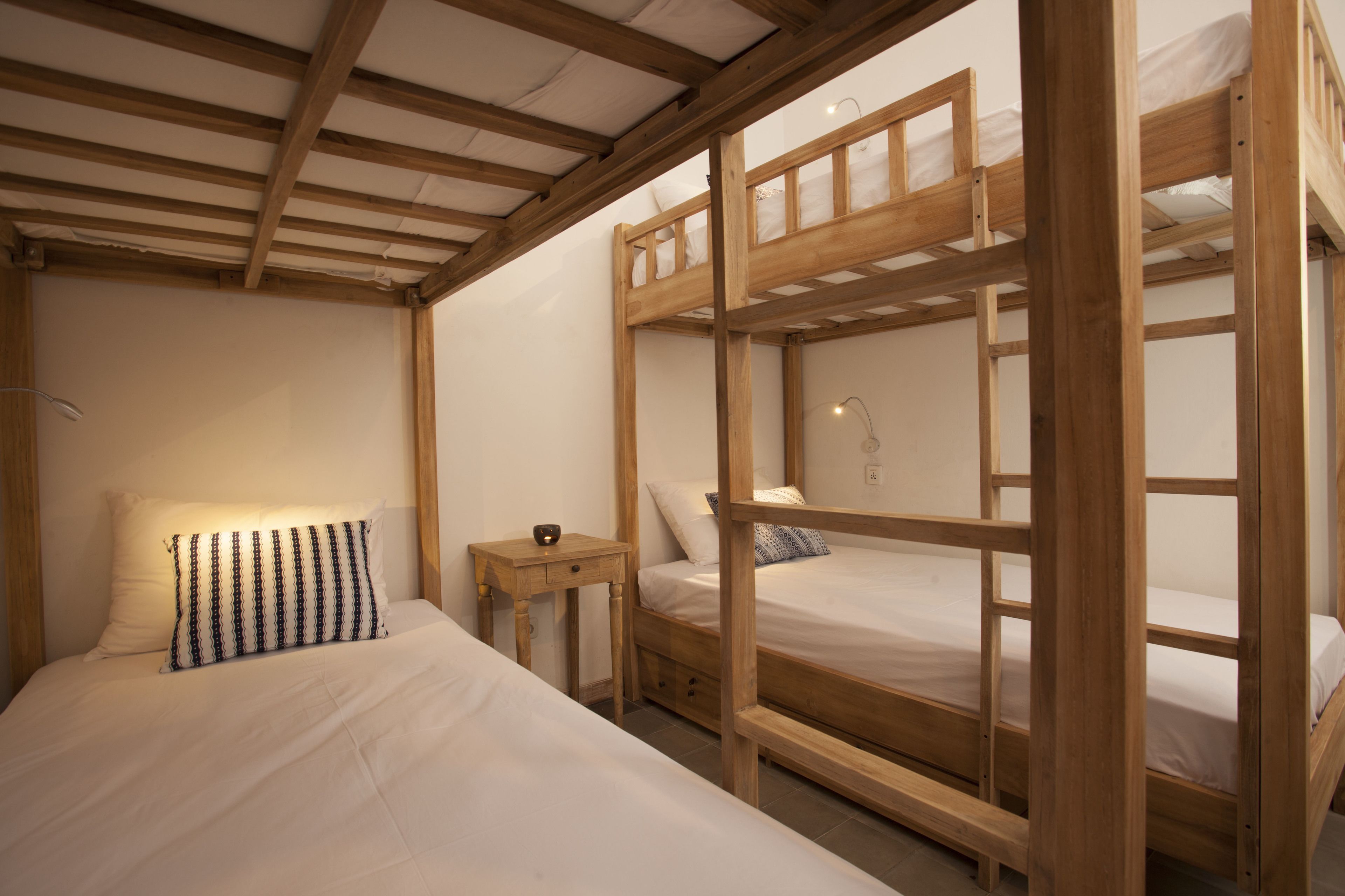 Een kamer met een stapelbed, een nachtkastje en een lamp.