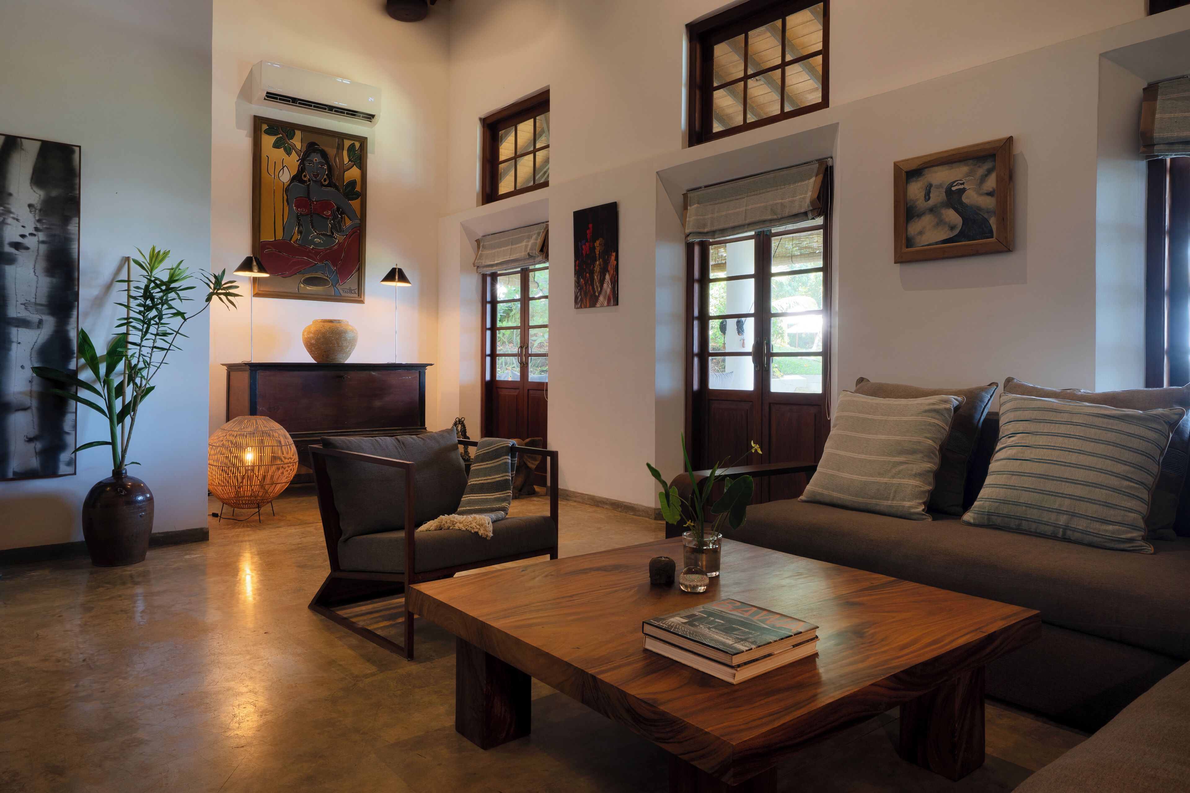 A living room with a sofa, a coffee table, a chair, a potted plant, and artwork on the walls.