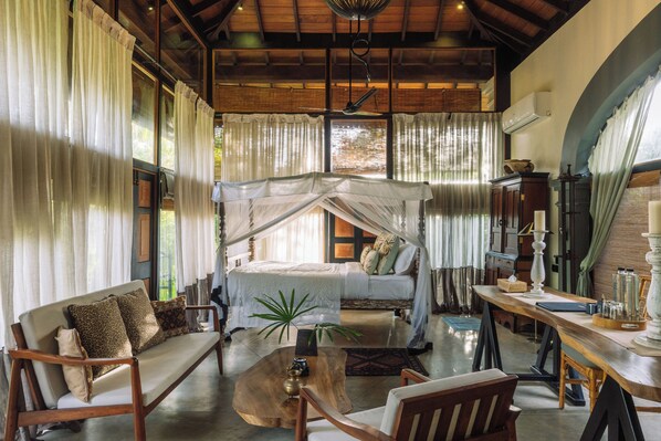Una habitación con una cama, una mesa de centro de madera, un sofá y una mesa de comedor con sillas.